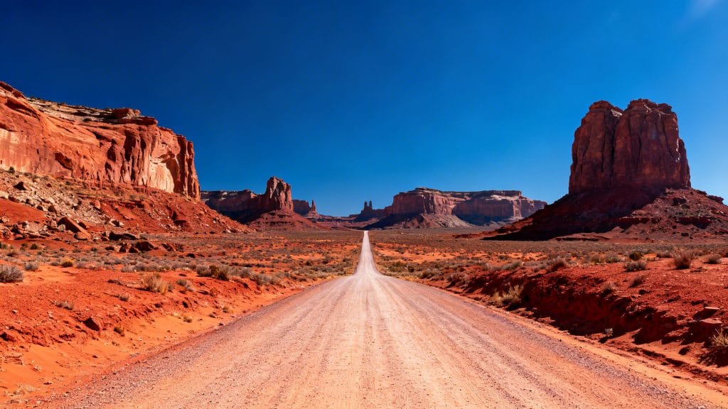 Route droite dans un désert rouge aux buttes