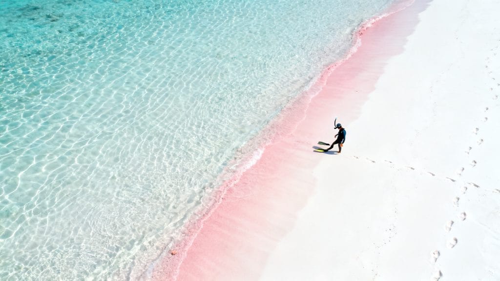 Plage au sable rosé et eau turquoise peu profonde