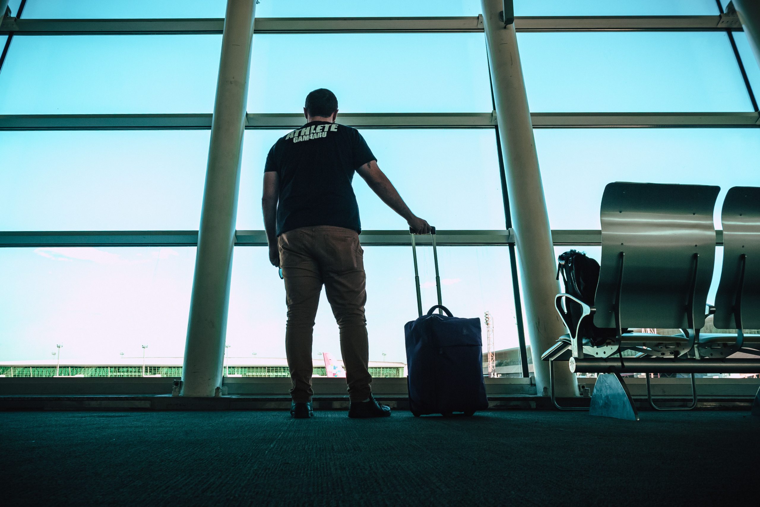 Voyageur au terminal avec valise cabine près d’une baie vitrée